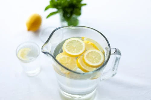 Free Top-down view of lemon slices in a glass pitcher filled with water, offering a refreshing drink option. Stock Photo