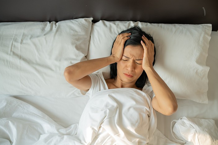 A person lying in bed with her hands on her headAI-generated content may be incorrect.